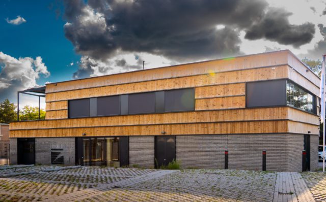 De gevelbekleding van de nieuwe gemeentewerf bestaat uit hergebruikt hout en hergebruikte stoeptegels